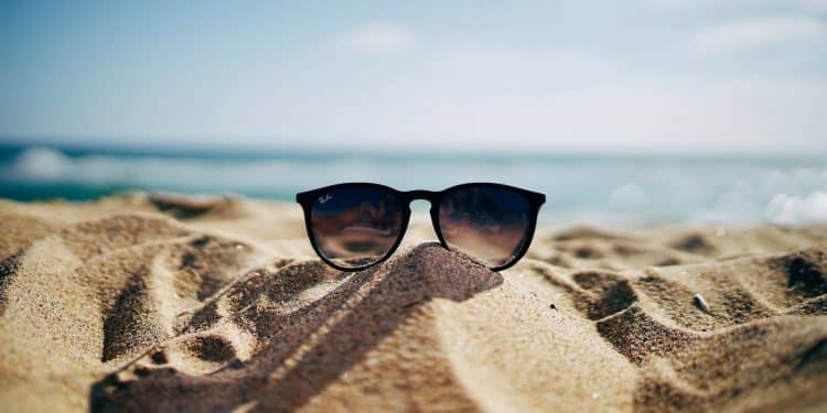 black Ray-Ban Wayfarer sunglasses on beach sand